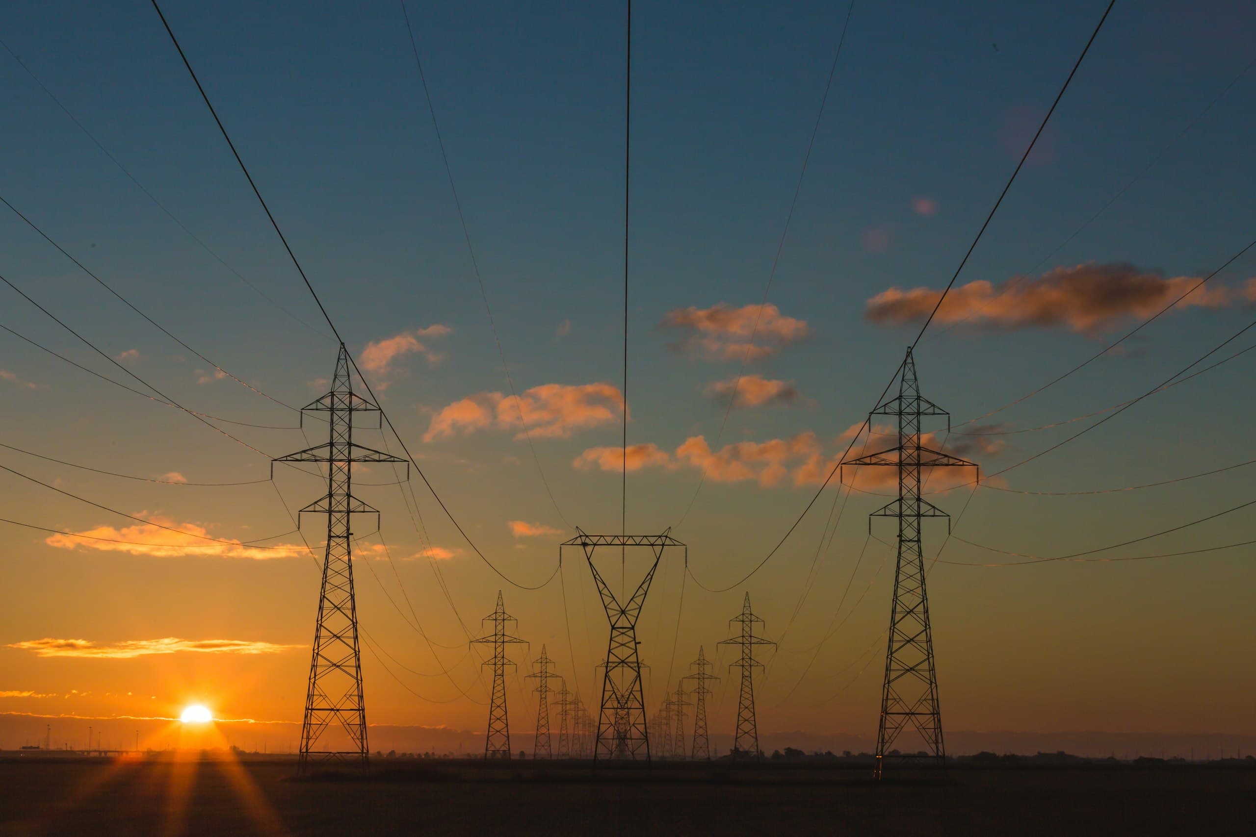 High-voltage transmission towers in open country at dusk